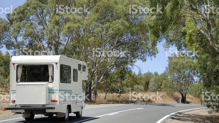 A motorhome rounding a bend on a tree-lined country road