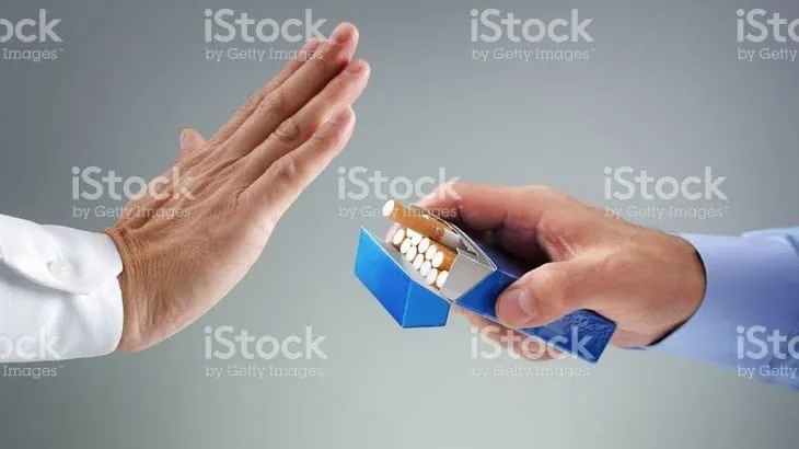 A raised hand refusing a cigarette offered from an open pack