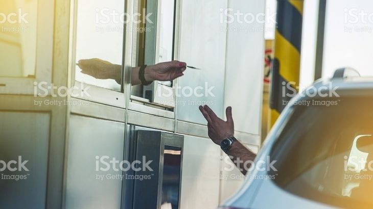 A driver paying at a toll booth window