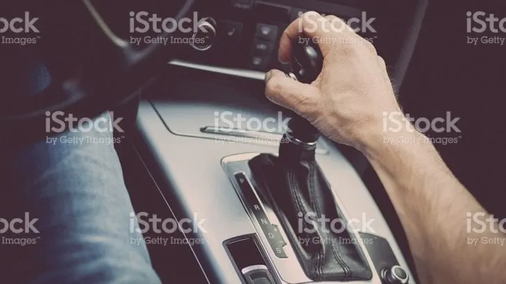 A driver's hand on an automatic transmission gear selector
