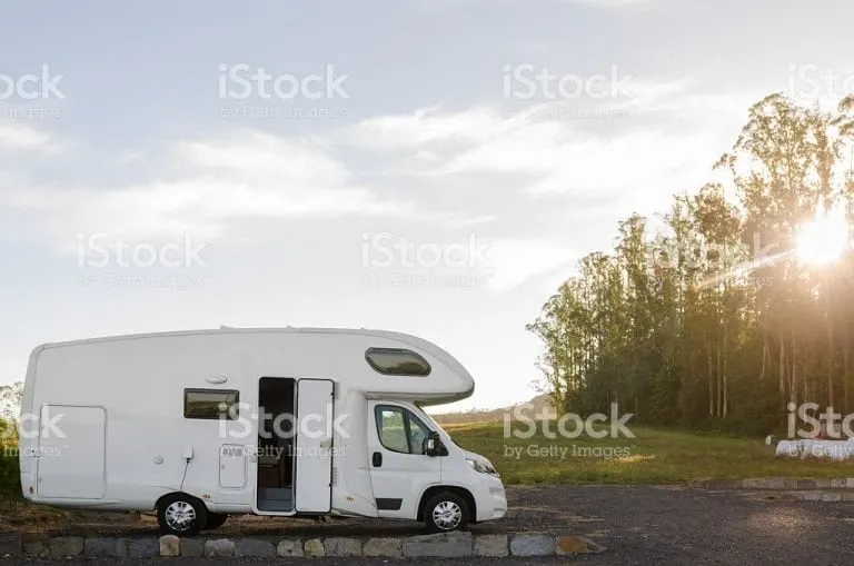 A motorhome parked with its door open at sunset