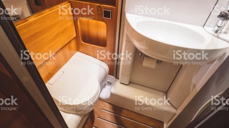 A compact campervan bathroom with a toilet and corner basin