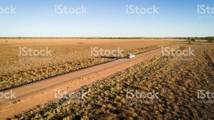 An aerial view of a campervan on an unsealed outback road