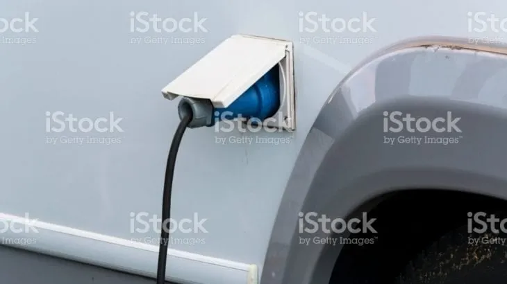 A power lead plugged into the external socket of a campervan