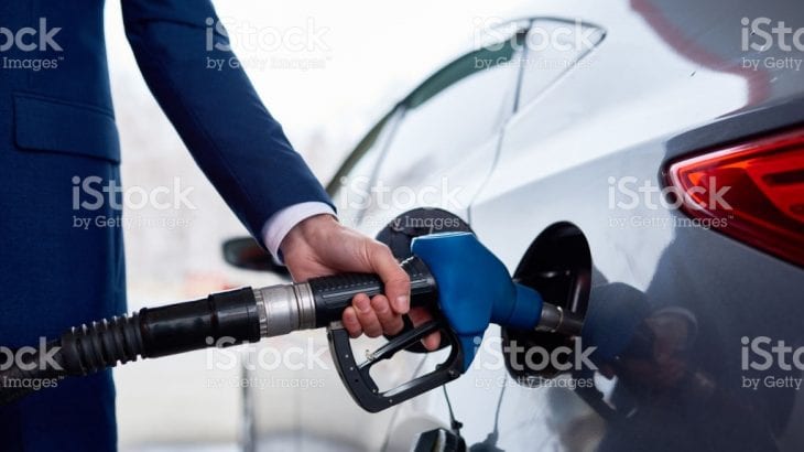 Side view closeup of unrecognizable businessman refueling gas tank iof luxury car in modern petrol station